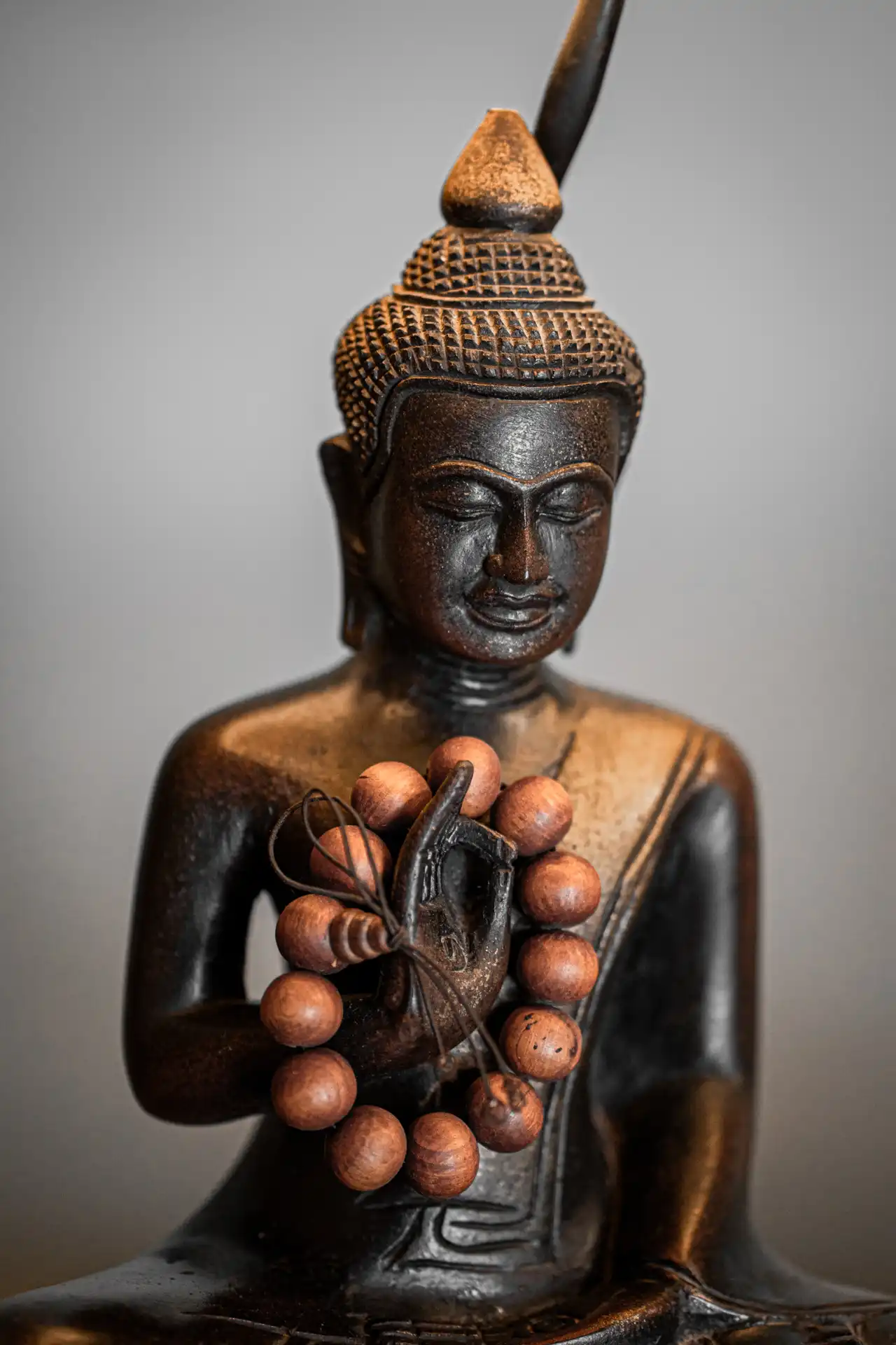 A carved Buddha statue with wooden prayer beads, part of the calm decor at Golden Hands