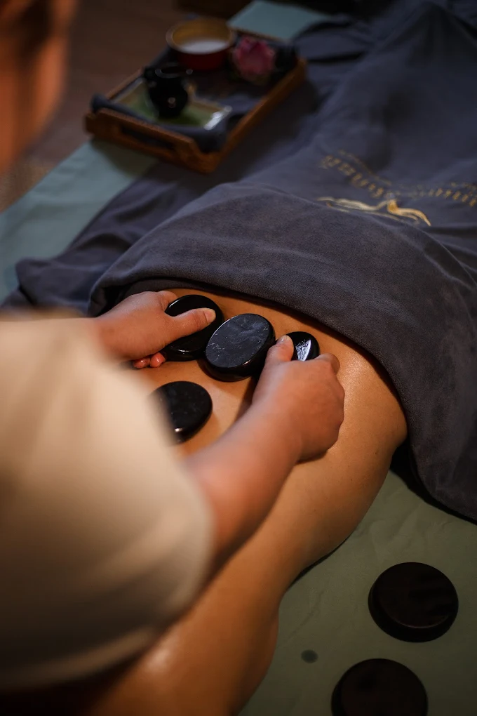 Therapist placing hot stones along a guest's back during a hot stone massage at Golden Hands