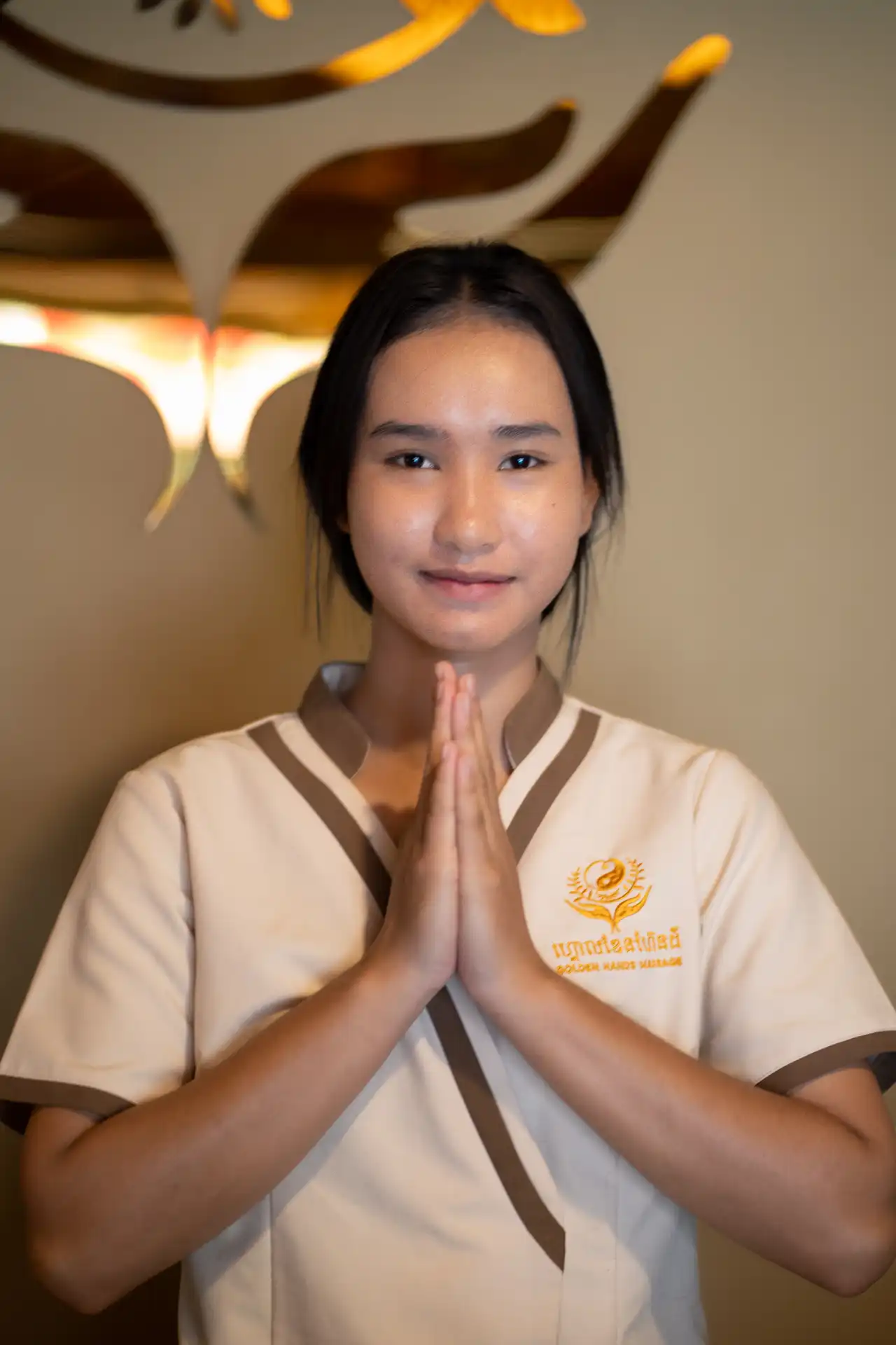 A Golden Hands therapist greeting guests with a traditional sampeah